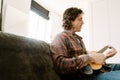 White bristle man playing ukulele while resting on couch Royalty Free Stock Photo