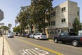 A white and brown apartment building with cars parked along the street and lush green trees with blue sky at Horny Corner Beach