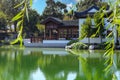 A white and brown Chinese pavilion in the garden with people walking through the pavilion near a deep green lake with lush greenry Royalty Free Stock Photo
