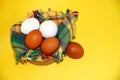 White and brown eggs and a bunch of green onions on a checkered napkin in a bowl on a yellow background Royalty Free Stock Photo