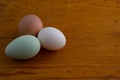 White, brown and green Araucana chicken egg laying on a wooden cutting board with copy space