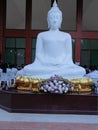 White Buddha image sitting on altar closeup with the Buddhist prayers in the temple.