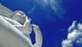 White Buddha sculpture under blue sky and white cloud