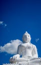White Buddha sitting on top of a mountain against the background of a bright summer sky in the city of Pai in the north