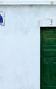 White building facade part with small window and green door