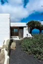 a white building with a small door and several palm trees