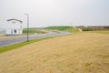 White building at turning of asphalted roads on grassy acclivity Royalty Free Stock Photo