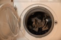 White built in washing machine with dirty clothes inside and open glass door Royalty Free Stock Photo