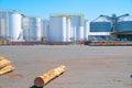 White bulk storage tanks across sealed yard with few logs on ground Royalty Free Stock Photo