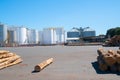 White bulk storage tanks across sealed yard with few logs on ground Royalty Free Stock Photo