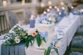 White bunk wedding cake decorated with flowers and leaves stands on a table with candles Royalty Free Stock Photo