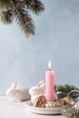 White bunnies, burning pink  candle , fir tree branches, decorative golden cones Royalty Free Stock Photo