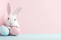 White Bunny with Pink and Blue Easter Eggs in Corner Setting. Soft Pastel Tones and Minimalistic Design Emphasize Royalty Free Stock Photo