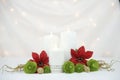 White burning candles with red poinsettia flowers and green roses Royalty Free Stock Photo