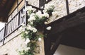 White bushy braided roses in garden on background of stone old house closeup on a sunny summer day, buds of delicate flowers Royalty Free Stock Photo