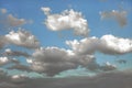 White bushy and fluffy clouds In the blue sky, with deep dark shadows on their bottoms from low layer of cloudiness. Royalty Free Stock Photo