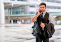 White business man holds the bottle of water and hand his suit or jacket on his arm, also use mobile phone to communicate with Royalty Free Stock Photo