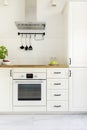 White cabinet in minimal kitchen interior with wooden countertop. Real photo Royalty Free Stock Photo