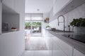 White cabinets in bright modern kitchen interior of house with terrace. Real photo