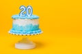 White cake with blue decorations and 20 candle on top Royalty Free Stock Photo