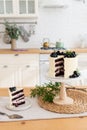 White cake with cream cheese, fresh blueberries and blackberries and piece of cake on the kitchen table. Confectionery, bakery