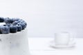 White cake decorated on top of blueberries stands on the table