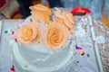 White cake yellow four flowers . Beige 4 tiered wedding cake decorated with mastic roses stands on the table on fabric background Royalty Free Stock Photo