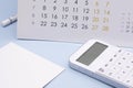 White calculator, calendar and note paper on blue background