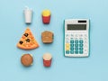 A white calculator and a set of fast food on a blue background Royalty Free Stock Photo