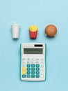 A white calculator and a small set of fast food on a blue background Royalty Free Stock Photo