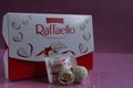 White candies round and halves in the background is a square rectangular gift box Raffaello stands on a pink fuchsia background si