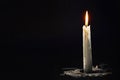 White candle burns in the dark on a black background in smoke Royalty Free Stock Photo