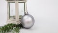 a white candle holder, a Christmas tree toy in the form of a silver frosted ball and a fir branch on a white background Royalty Free Stock Photo