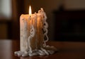 A white candle with intricate wax drippings is placed on a wooden surface. The candle is lit, Royalty Free Stock Photo