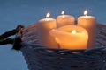 White candles burning outdoors in a rattan basket