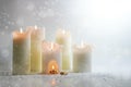 White candles burning in the snow, in one is a carve with a warm campfire, surreal winter still life, heat and energy concept,