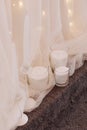 White candles on gray carpet with curtain