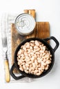 White canned kidney beans, with metal can, in cast iron frying pan, on white stone  surface, top view flat lay Royalty Free Stock Photo