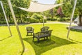 White canvas gazebo and plastic benches in a green lawn