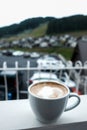 White cappuccino mug on a balcony. Beautiful quiet morning in the mountains. Fresh cup of coffee with foam on a balcony outside. Royalty Free Stock Photo