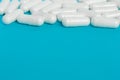 White capsules of medicine lie on a blue background Royalty Free Stock Photo