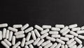 White capsules, pills on a black background with place for text. Royalty Free Stock Photo