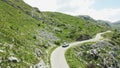 A white car drives along the beautiful green mountain road in Montenegro. Aerial Royalty Free Stock Photo