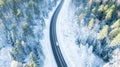 White car drives empty road in forest in the cold Finnish winter. Tourists on road trip cruising through the idyllic snow covered