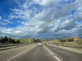 a white car driving around a curve on a freeway through the rainbow coming out of the storm on a cloudy day Royalty Free Stock Photo