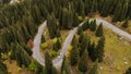 A white car driving on a serpentine road in the mountains in autumn