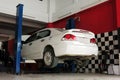 A white car is lifted up for the repairing process at the garage