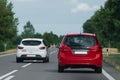 A white car overtakes a red car on an open road