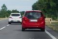 A white car overtakes a red car on an open road