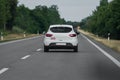 A white car overtakes a red car on an open road